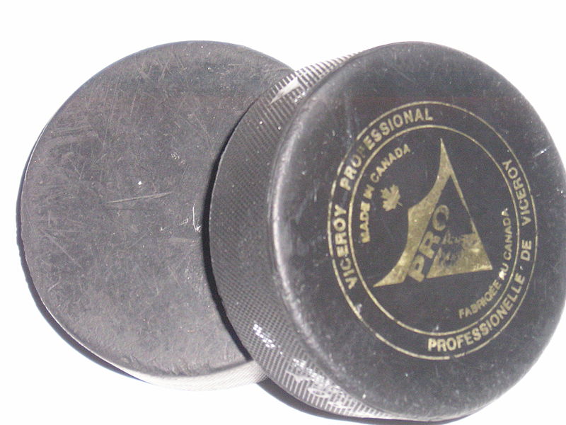 2 hockey pucks on white sheet of paper photographed by myself. One contains the logo of a Canadian puck company.