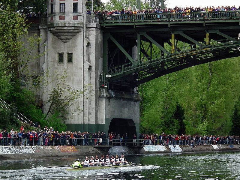 English:   University of Washington men's varsity crew competes in the 25th Annual Windermere Cup during Opening Day of Boating Season, Seattle, Washington, USA.  Montlake Bridge is in the background.